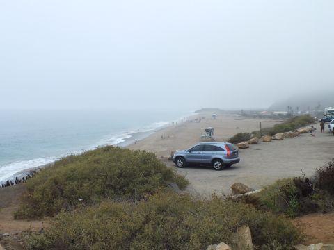 2003 Ford Crown Victoria - Photograph of an SUV parked on a coastal overlook above a hazy beach, not a technical document.