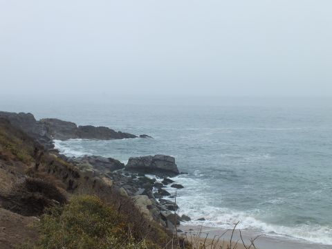 2003 Ford Crown Victoria - misty ocean view with rocky points and a small pebbly beach fading into heavy coastal haze.