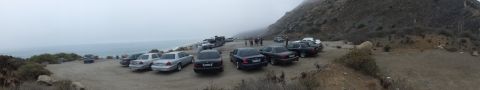 2003 Ford Crown Victoria - panoramic view of numerous sedans parked along a gravel lot on a foggy hillside above the ocean.