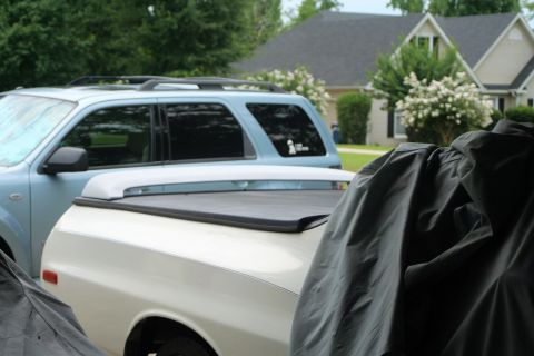 1976 Ford Ranchero - A white pickup truck with a tonneau cover is parked next to a blue SUV in a driveway.