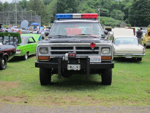 1991 Ford LTD Crown Victoria - Head-on view of a black-and-white Dodge Highway Patrol SUV with winch and lightbar on grass among classic show cars.