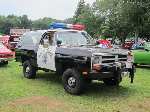 1991 Ford LTD Crown Victoria - black-and-white police SUV marked Highway Patrol, fitted with a roof light bar and front-mounted winch, parked on grass at a car show.