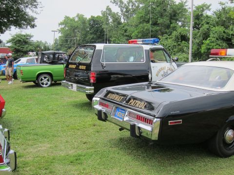 1991 Ford LTD Crown Victoria - Rear three-quarter view of two black-and-white Highway Patrol vehicles, an SUV and a sedan, lined up on grass at an outdoor show.