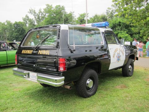 1991 Ford LTD Crown Victoria - Rear three-quarter view of a black-and-white SUV lettered Highway Patrol with a roof light bar, parked on grass among show vehicles.