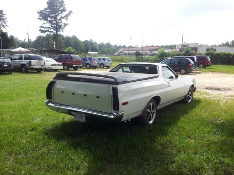 1976 Ford Ranchero - This white Ford Ranchero pickup is parked on a grassy lot with other vehicles in the background.