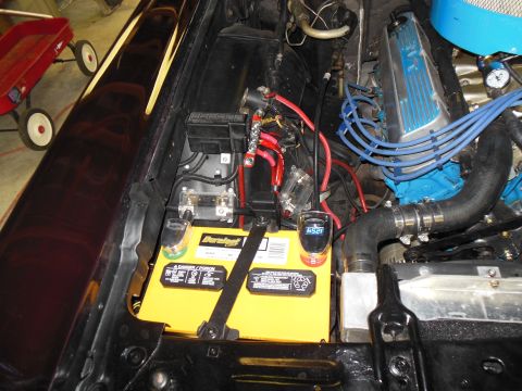 1979 Ford Ranchero - Detail of the driver-side engine bay showing a yellow Duralast Gold battery on a black tray with a hold-down strap, two in-line ANL fuse ho…