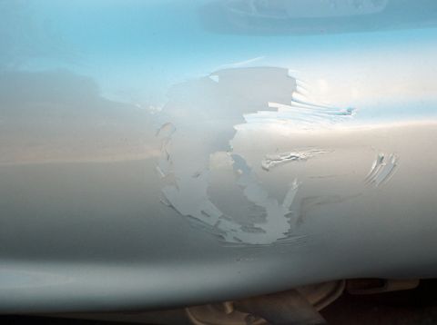 1998 Ford Taurus - Damage to the car's bodywork shows peeling paint and deep scratches, indicating wear and tear.