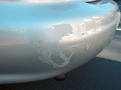 1998 Ford Taurus - Damage to the rear bumper of a car, showing chipped and scraped paintwork.