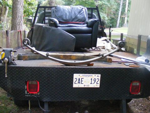1978 Ford Bronco - Leaf spring and a recliner chair are loaded onto a flatbed truck. The license plate reads 2AE 192.