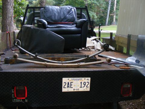 1978 Ford Bronco - A flatbed truck carries a recliner and vehicle parts, with a Mississippi license plate visible.