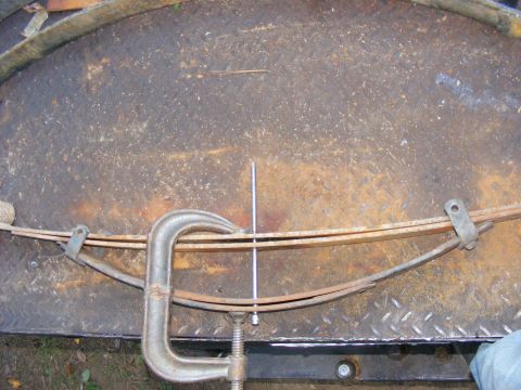 1978 Ford Bronco - A leaf spring is secured with a C-clamp, likely for repair or modification.