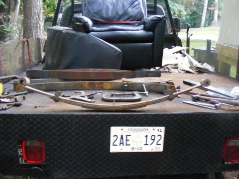 1978 Ford Bronco - A collection of automotive parts and furniture are loaded onto a truck bed, ready for transport or work.