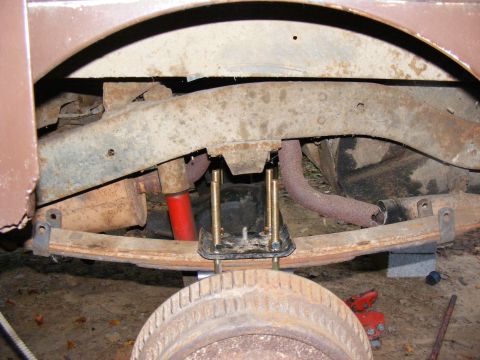 1978 Ford Bronco - The undercarriage of a vehicle shows leaf springs and red shock absorbers, with visible rust on the frame.