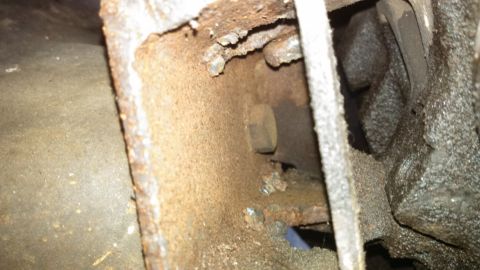 1979 Ford Bronco - Close-up of heavily rusted metal framing with a bolt, likely from a vehicle's undercarriage.