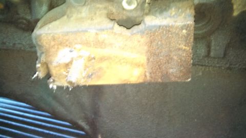 1979 Ford Bronco - Close-up view of a rusty engine component with exposed bolts and metalwork.