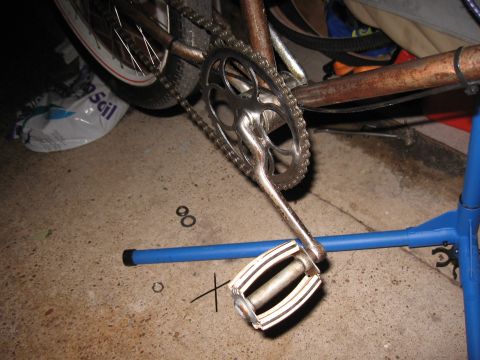 1994 Ford Bronco - Close-up view of a bicycle's crankset, pedal, and chain assembly, resting on a concrete surface.