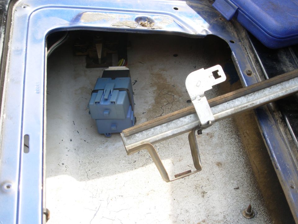 Inside tailgate cavity with blue relay module, white latch bracket and metal rail