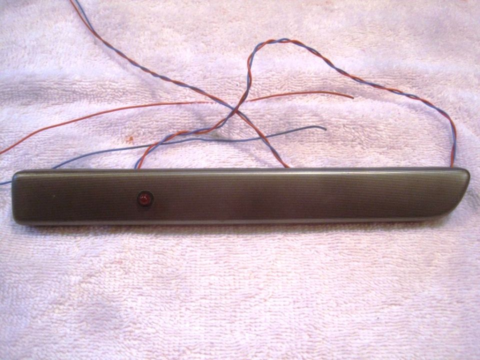 Dark gray interior trim piece with red lens and wires