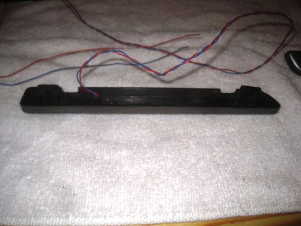 black plastic automotive part with red and blue wires attached
