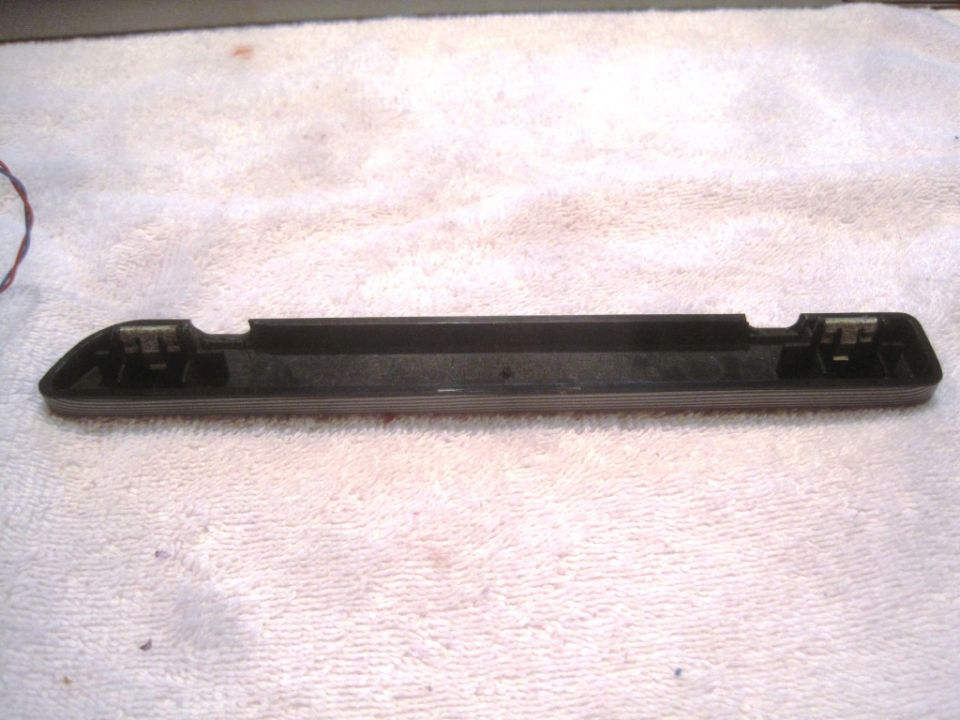 Black plastic trim piece with metal clips on a white towel. Supermotors.net logo at bottom right