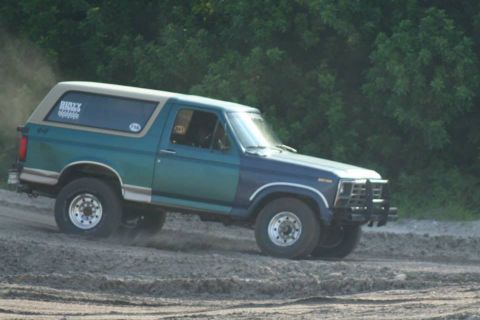 1996 Ford Bronco - Ford Bronco with two-tone paint kicks up dust while driving on a dirt track.