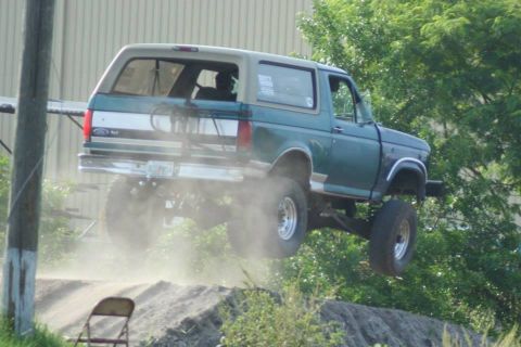 1996 Ford Bronco - This lifted Ford Bronco is captured mid-air, demonstrating its off-road capabilities.