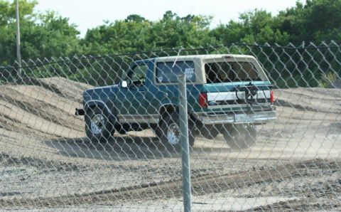 1996 Ford Bronco - A 1996 Ford Bronco navigates a dirt track, kicking up dust behind it.
