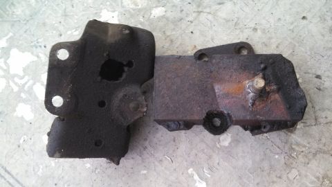 1979 Ford Bronco - Two rusty metal automotive parts are shown on a concrete surface.