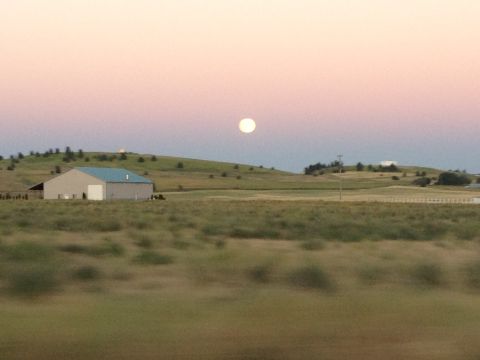 2005 Jeep Wrangler - A full moon is visible in the sky above a barn and grassy hills at dusk.