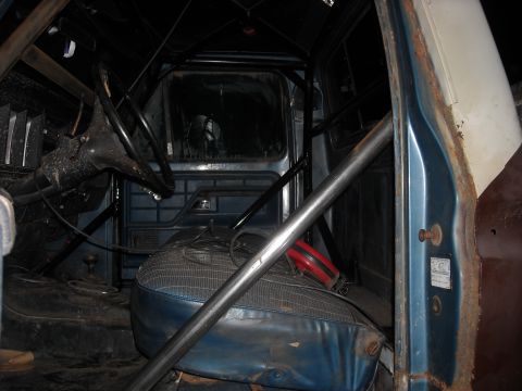 1979 Ford F-150 - The interior of a 1979 Ford F-150 features a roll cage and blue vinyl seats.