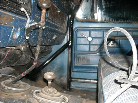 1979 Ford F-150 - Interior of a blue truck cab, dual gear shifters and a blue door panel with a manual window crank.
