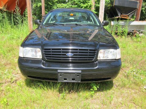 2001 Ford Crown Victoria - The front grille and headlights of a black Ford Crown Victoria are visible in this outdoor shot.