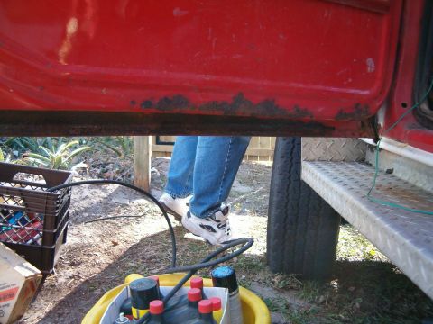 1979 Ford Bronco - Rusted lower door sill and running board on a red truck, with a person standing nearby.