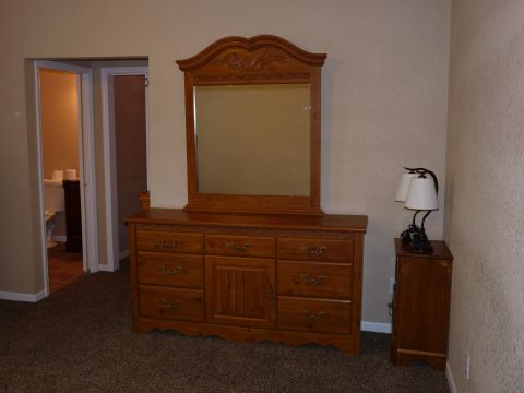 2006 Ford E350 - A bedroom scene with a wooden dresser, mirror, and a lamp on a nightstand.