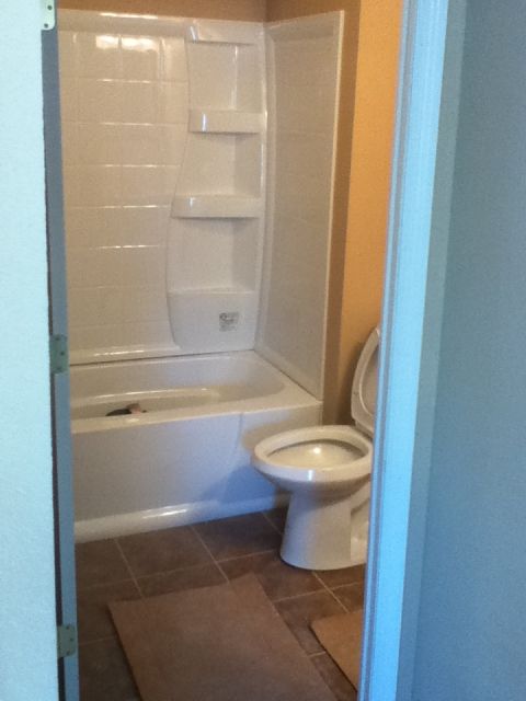 2006 Ford E350 - A bathroom scene a white bathtub and toilet with tiled flooring.
