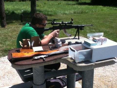 2006 Ford E350 - Man at shooting range with rifle, ammunition, and gun case on a picnic table.