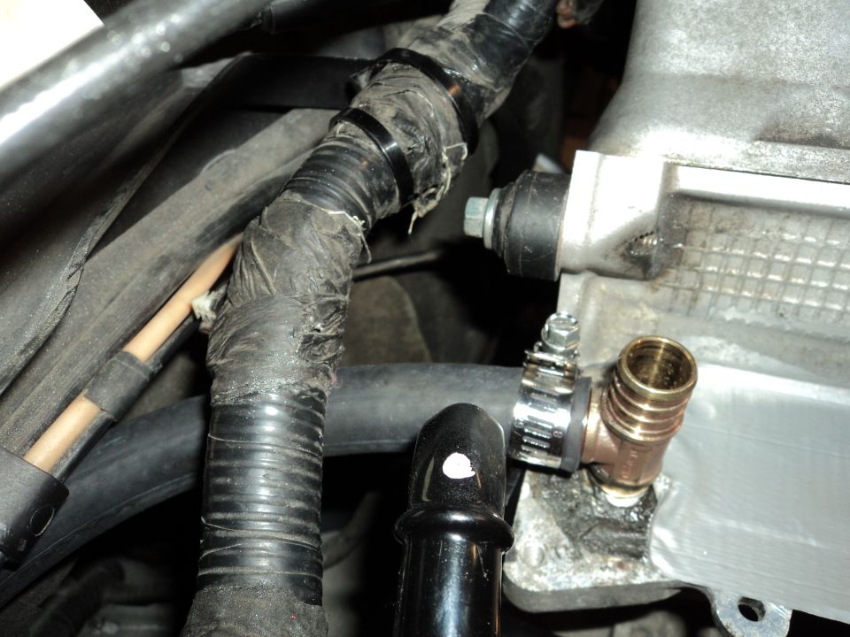 Engine bay wiring harness with black tape and zip ties, connected to a brass T-fitting with a hose clamp