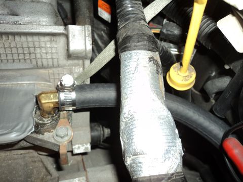 2004 Mercury Grand Marquis - A close-up view of various engine components, including hoses and metal parts, some of which are wrapped in tape.