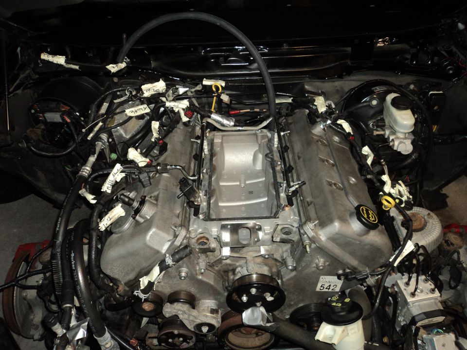 Engine bay with V8 engine, wiring harnesses, and a Supermotors.net watermark