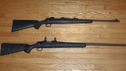 2000 Dodge 1500 - Two rifles are displayed on a wooden floor, each with a black stock and a long barrel.