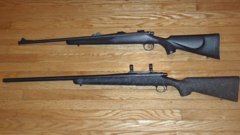 2000 Dodge 1500 - Two rifles are displayed on a wooden floor. One rifle has a smooth black stock, the other has a speckled stock.
