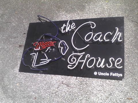 2003 Ford Crown Victoria - A damaged neon sign for "the Coach House" and "@ Uncle Fattys" lies on the ground.