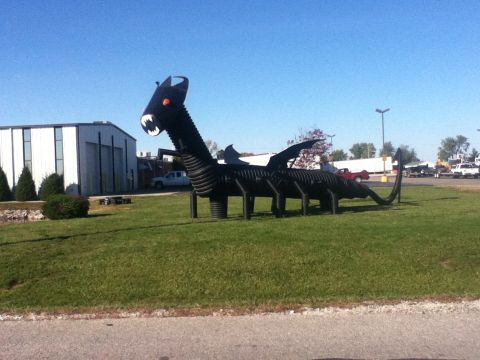 2006 Ford E350 - A large, black, pipe-constructed dragon sculpture stands on a lawn under a clear blue sky.