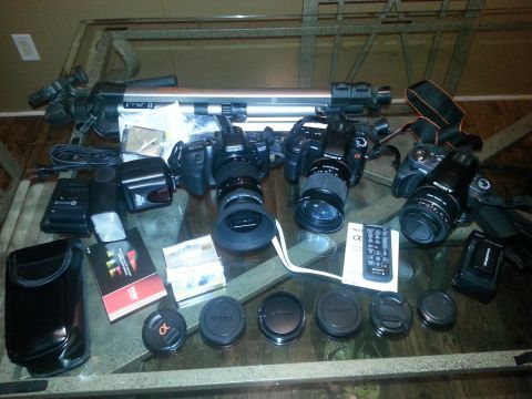 1982 Jeep Wagoneer - A collection of Sony Alpha cameras, lenses, and accessories are laid out on a glass table.