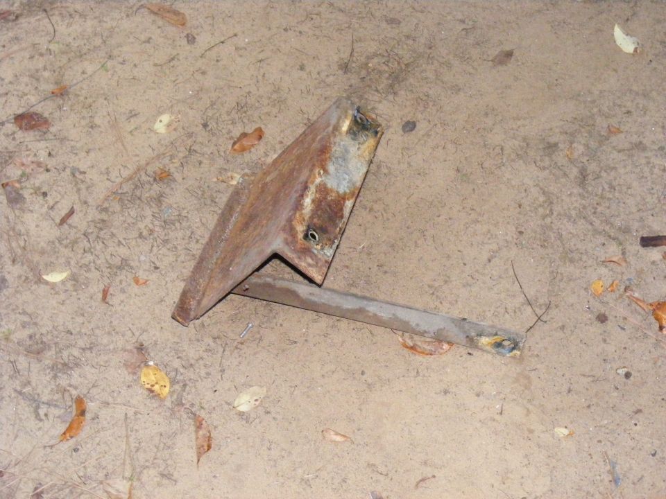 Rusted metal bracket on dirt ground