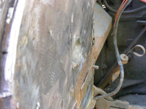1978 Ford Bronco - A close-up view of a damaged vehicle body panel reveals exposed wiring and signs of rust.