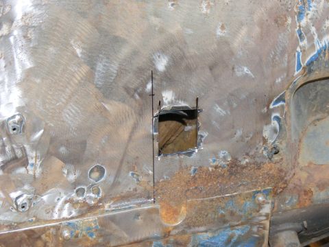 1978 Ford Bronco - A square has been cut out of a heavily rusted metal panel, revealing wood underneath.
