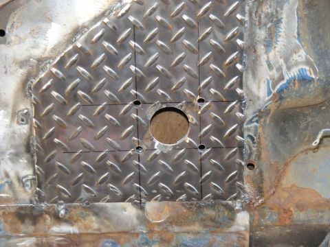 1978 Ford Bronco - A custom metal patch with drilled holes is welded onto a rusty vehicle floor panel.