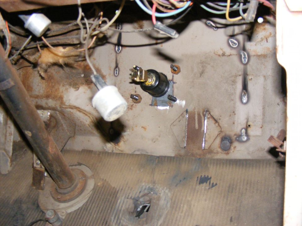 Close-up of vehicle interior showing wiring harness, ignition switch, and steering column base