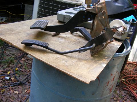 1978 Ford Bronco - Vehicle pedals are displayed on a wooden board, resting on a blue barrel outdoors.
